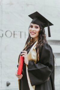 selective focus photo of smiling woman in black academic dress holding diploma posing